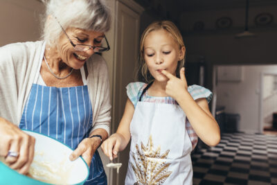 grandmother and granddaughter baking with ground cinnamon and other ingredients in the kitchen