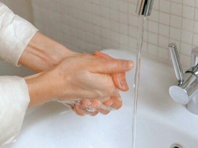 woman washing hands with soap in a bathroom sink