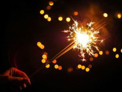 a woman's hand holding three lit sparklers